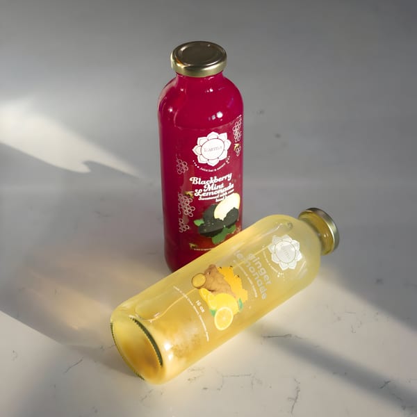 Two Karma Juice Bar & Eatery bottles, Blackberry Mint and Ginger Lemonade, on a white surface.